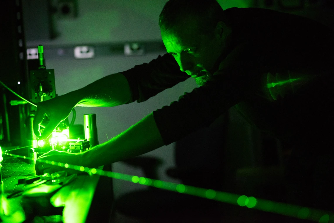 Man working in a lab with green light in the background